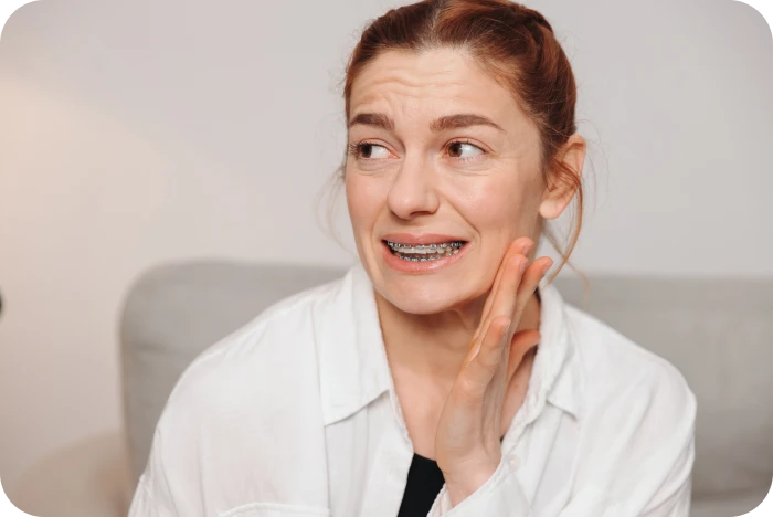 Femme ressentant une sensibilité dentaire après un ajustement orthodontique