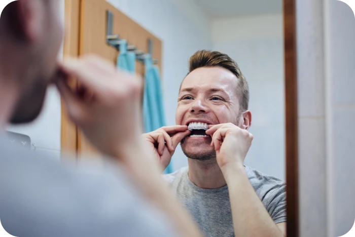 Homme mettant en place son aligneur transparent devant le miroir