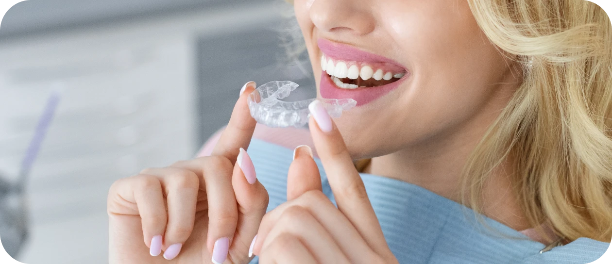 Femme souriante tenant un aligneur invisible transparent